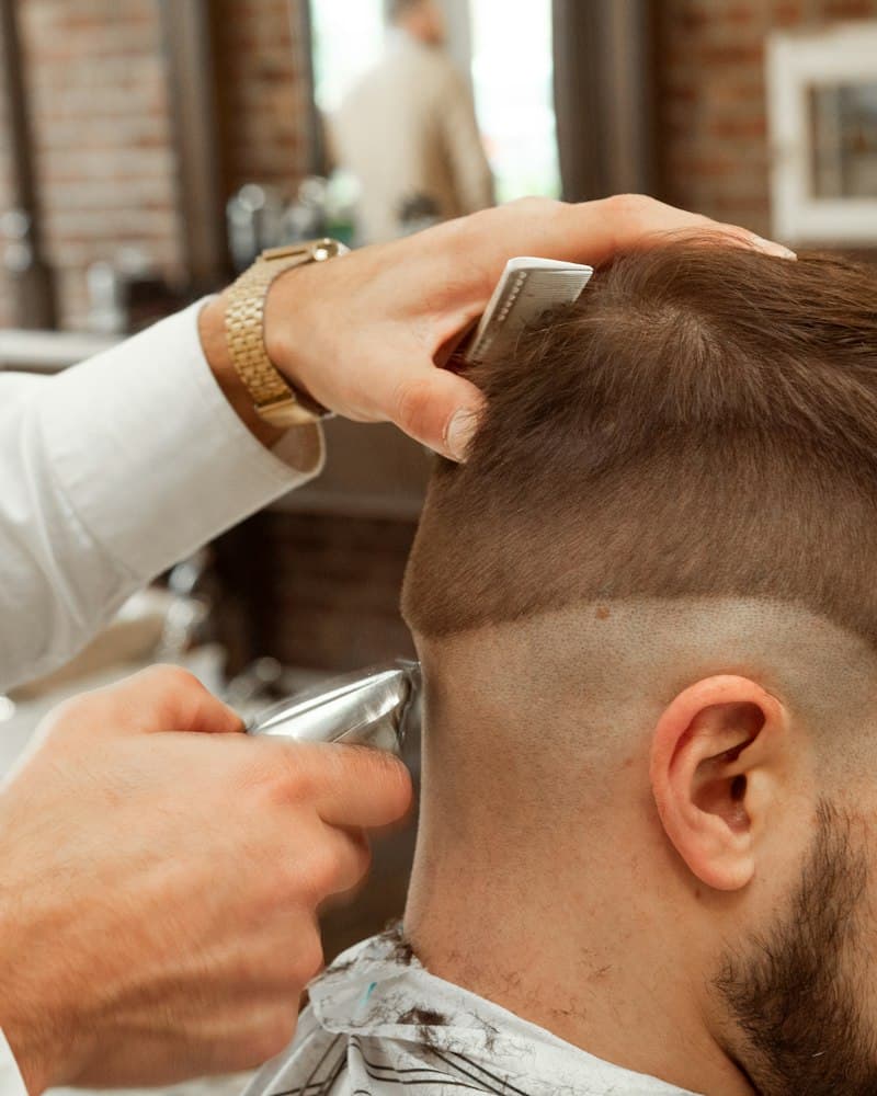 Barbeiro aparando o cabelo de um cliente