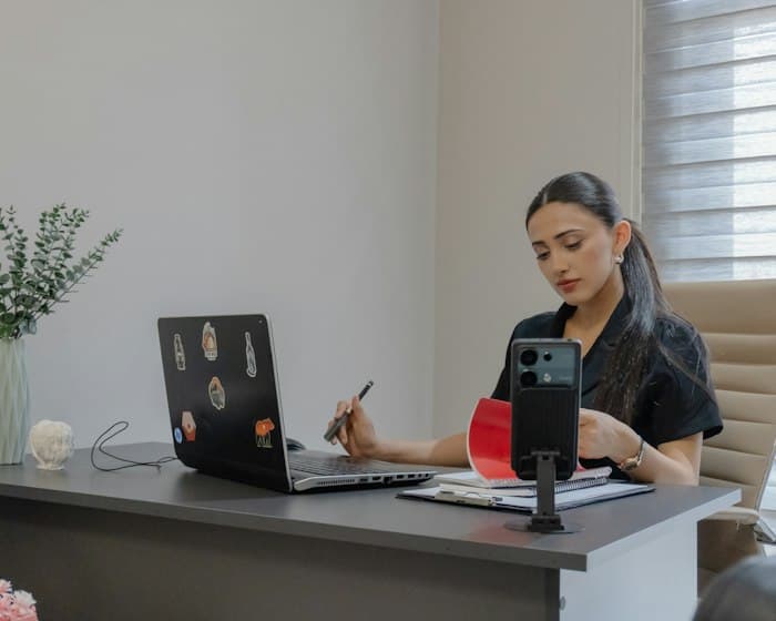 Profissional no escritório tentando organizar divulgação pelo celular