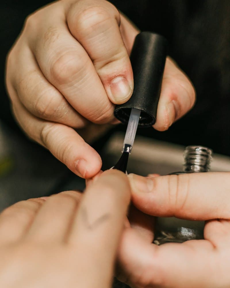 Manicure aplicando esmalte em uma cliente
